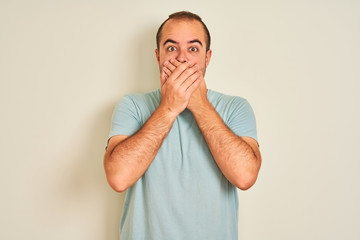 Sticker - Young man wearing blue casual t-shirt standing over isolated white background shocked covering mouth with hands for mistake. Secret concept.