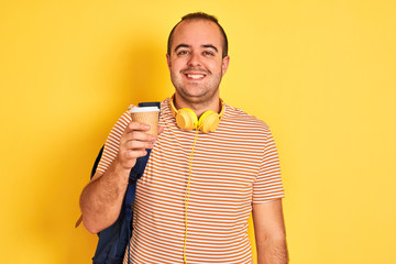 Poster - Student man wearing backpack headphones drinking coffee over isolated yellow background with a happy face standing and smiling with a confident smile showing teeth