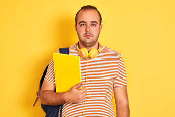 Poster - Student man wearing backpack headphones holding notebook over isolated yellow background with a confident expression on smart face thinking serious