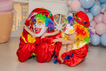 Wall Mural - Funny clowns from the circus. Clown boy and clown girl show emotions