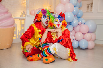 Wall Mural - Funny clowns from the circus. Clown boy and clown girl show emotions