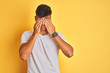 Young indian man wearing white t-shirt standing over isolated yellow background rubbing eyes for fatigue and headache, sleepy and tired expression. Vision problem
