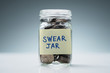 Swear Jar Filled With Coins Against Grey Background