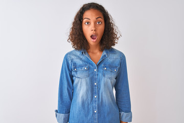 Canvas Print - Young brazilian woman wearing denim shirt standing over isolated white background afraid and shocked with surprise and amazed expression, fear and excited face.