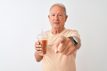 Canvas Print - Senior man wearing striped t-shirt drinking tomato smoothie over isolated white background pointing with finger to the camera and to you, hand sign, positive and confident gesture from the front