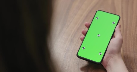 Sticker - Slow motion handheld shot of young woman holding smartphone over walnut table