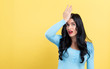 Young woman making a mistake on a yellow background