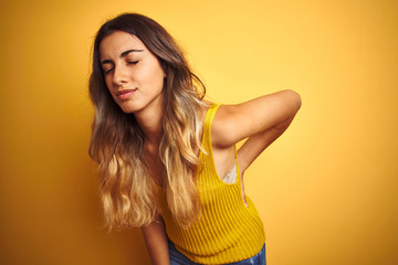 Canvas Print - Young beautiful woman wearing t-shirt over yellow isolated background Suffering of backache, touching back with hand, muscular pain