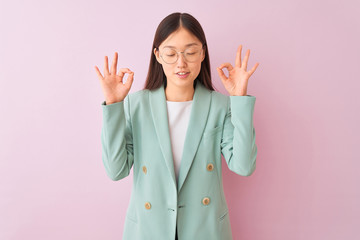 Sticker - Young chinese businesswoman wearing jacket and glasses over isolated pink background relax and smiling with eyes closed doing meditation gesture with fingers. Yoga concept.