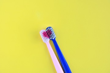 Toothbrush for personal healthcare dental care on yellow background.Two bright toothbrushes with red heart. Toothbrush for personal healthcare. St. Valentine's Day concept. Lovers toothbrushes