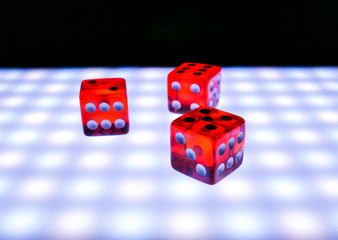 Red dice on a luminous surface on a black background, concept of board games