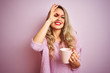 © Krakenimages.com - Young beautiful woman wearing sweater drinking a cup of coffee over pink isolated background with happy face smiling doing ok sign with hand on eye looking through fingers