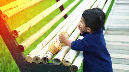 The cute boy in the nature, the outdoor lifestyle of Thai children sitting on a rice farm after rain before sunset, the children eat sticky rice, use the countryside in the way of the farmers concept