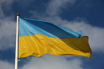 Wall Mural - flag of ukraine waves on white flagpole against blue sky with nice white clouds