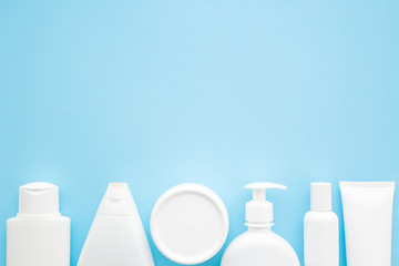 Wall Mural - Different white toiletries on light pastel blue table. Care about face, hands, legs and body skin. Women beauty products. Empty place for text or logo. Flat lay. Top down view.