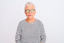 Senior Grey-haired Woman Wearing Striped Navy T-shirt Glasses Over Isolated White Background Relaxed With Serious Expression On Face. Simple And Natural Looking At The Camera.