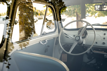 Wall Mural - Interior of small white vintage car on the street. No people. White steering wheel.