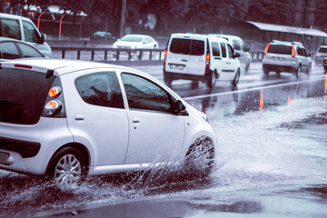 Ukraine. Kiev - 05,12,2019 Spraying water from the wheels of a vehicle moving on a wet city asphalt road. The wet wheel of a car moves at a speed along a puddle on a flooded city road during rain.