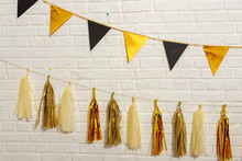 Gold Black Paper Garlands On A White Brick Wall.  Paper Foil Flags On A String. Tissue Paper Tassels Garland Bunting Happy Birthday Wedding Party Decor. Matte And Glossy Gold Garland For Party 
