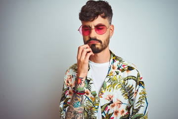 Wall Mural - Man with tattoo on vacation wearing summer shirt sunglasses over isolated white background thinking looking tired and bored with depression problems with crossed arms.