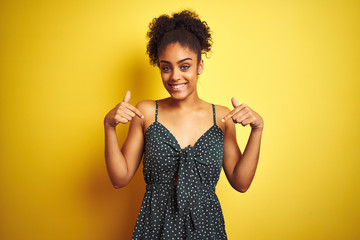 Sticker - African american woman wearing summer casual green dress over isolated yellow background looking confident with smile on face, pointing oneself with fingers proud and happy.