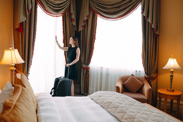 Young women with suitcase are staying in a hotel room.