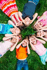 A group of children lying on the green grass in the Park. The interaction of the children.