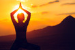 © davit85 - Silhouette of young woman practicing yoga or pilates at sunset or sunrise in beautiful mountain location.