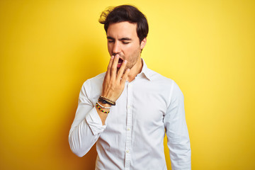 Poster - Young handsome businessman wearing elegant shirt standing over isolated yellow background bored yawning tired covering mouth with hand. Restless and sleepiness.