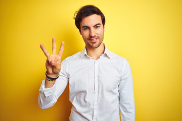 Wall Mural - Young handsome businessman wearing elegant shirt standing over isolated yellow background showing and pointing up with fingers number three while smiling confident and happy.