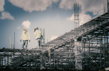 Construction  working on a construction site on high ground heavy industry and safety concept over  natural background sunset 