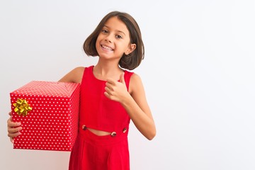 Wall Mural - Beautiful child girl holding birthday gift standing over isolated white background happy with big smile doing ok sign, thumb up with fingers, excellent sign