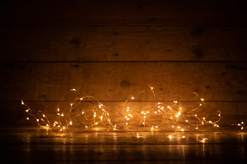 Golden bokeh lights on rustic wooden boards  -  Christmas and holidsy background texture with empty space -      Copy space for text 