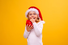 Little Blonde Girl In Santa Hat Holding Piggy Bank On Yellow Background Isolate, Space For Text