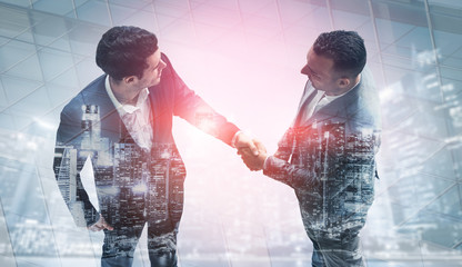 Wall Mural - Double exposure image of business people handshake on city office building in background showing partnership success of business deal. Concept of corporate teamwork, trust partner and work agreement.