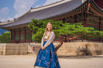 Young caucasian female tourist in hanbok national korean dress at Korean palace. Travel to Korea concept. National Korean clothing. Entertainment for tourists - trying on national Korean clothing