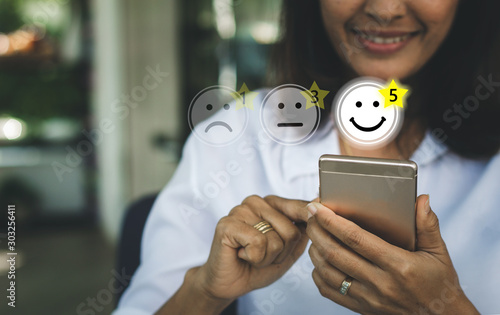 Fotografía Businesswoman pressing face emoticon on virtual touch screen at smartphone