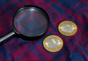 Rare coins with a magnifying glass. Collecting coins and banknotes. Coins of precious metals lie on the fabric. Collection of coins and pennies. Numismatics.