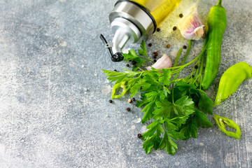 Wall Mural - Herbs and seasoning background. Parsley, chili pepper, garlic, sea salt and others with olive oil on a stone table. Copy space.