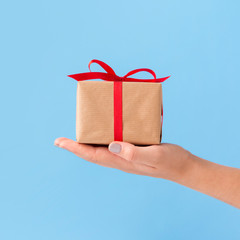 Woman holding Christmas present on blue background