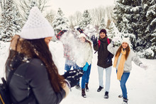 Young Friends In Winter Coats Having Snowball Fight In Winter Nature