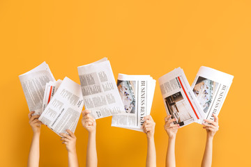 female hands with newspapers on color background