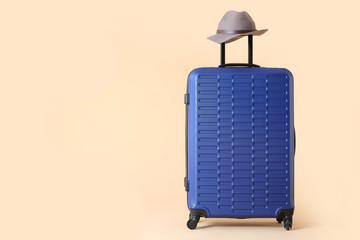 Packed suitcase and hat on color background. Travel concept