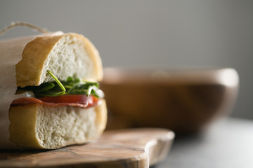 closeup ciabatta sandwich with salami and mozzarella cheese on olive board