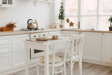 Wall Mural - Modern new bright kitchen interior with white furniture and a dining table. gas stove with kettle and pan