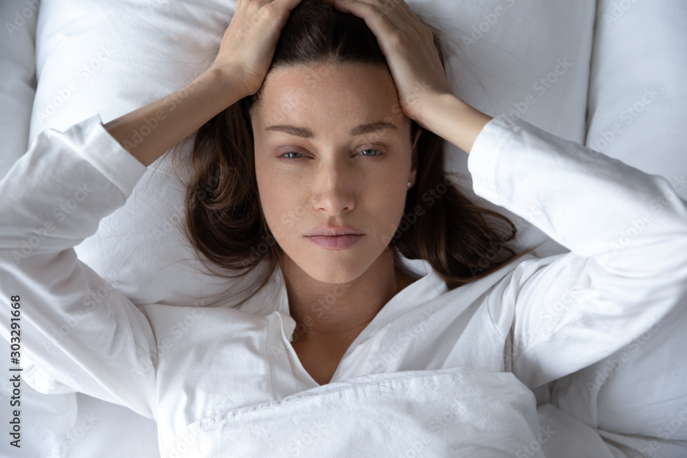 Disturbed woman lying awake in bed suffer from insomnia headache - obrazy, fototapety, plakaty 
