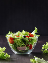 fresh  salad with vegetables and ham in a glass bowl on a dark wooden table with copy space