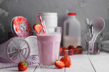 Wall Mural - Strawberry protein shake on a white wooden background. Fresh milkshake with strawberries on a light table. A glass of strawberry smoothie.