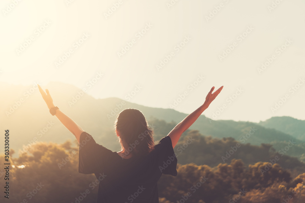Copy space of woman rise hand up on top of mountain and sunset sky abstract background. - obrazy, fototapety, plakaty 