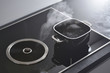 Modern electric induction cooker with built-in ventilation and extractor hood which draws steam from boiling water in a pan. Steam from a boiling pot is drawn into the integrated range hood